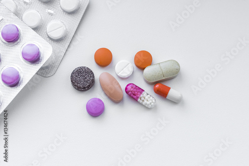 Many different pills scattered on the table for treatment during illness