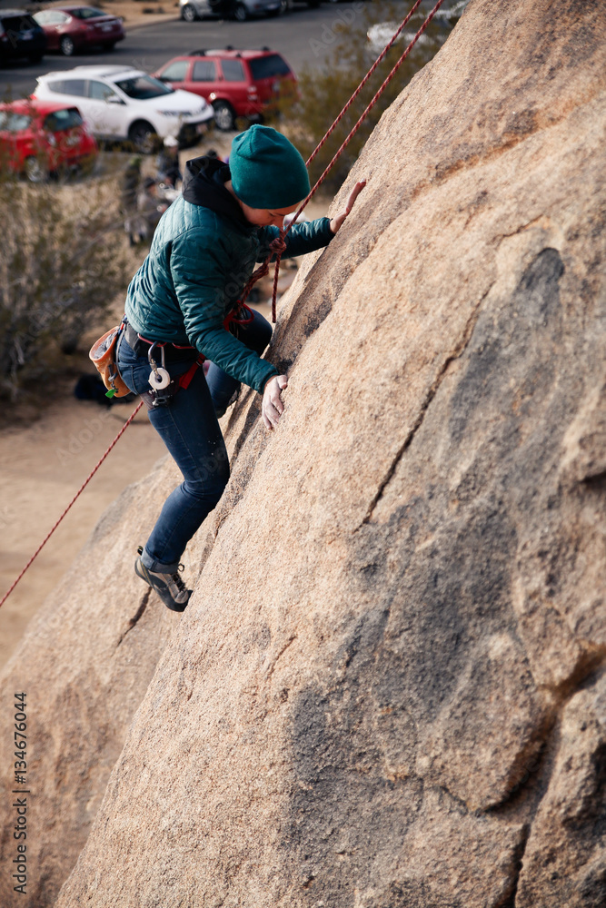 Young caucasian woman dressed for cold weather rock climbing in the desert climbs a cliff Young caucasian woman dressed for cold weather rock climbing in the desert climbs a cliff