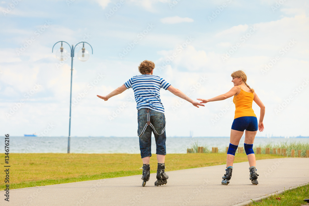 Obraz premium Young couple on roller skates riding outdoors