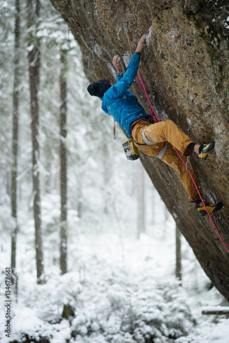 Outdoor winter sport. Rock climber ascending a challenging cliff. Extreme sport climbing.