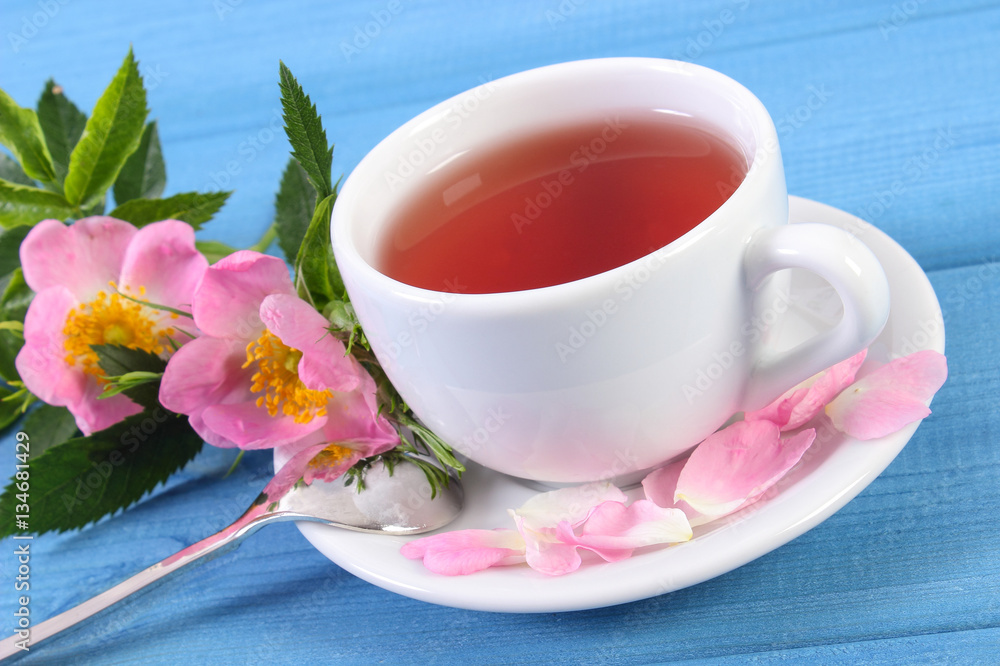 Cup of tea and wild rose flower on blue boards Cup of tea and wild rose flower on blue boards