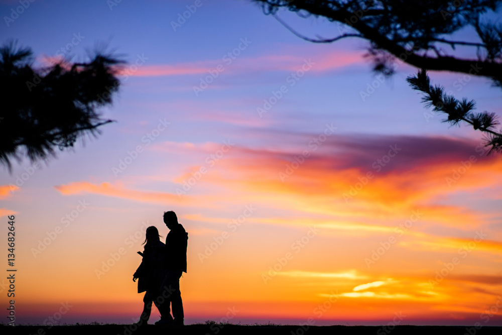 Silhouette of Couple walking between Twilight Light at  sea.