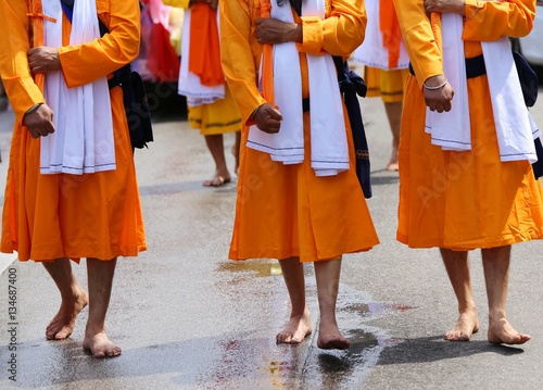 barefoot men of Sikh Religion with long orange clothes walk bare