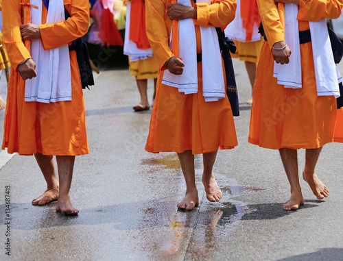 men of Sikh Religion with long orange clothes walk barefoot with