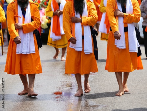 men of Sikh Religion with long orange clothes walk barefoot with