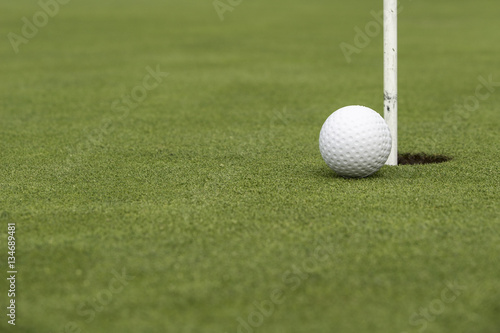 Golf ball close to pin and hole