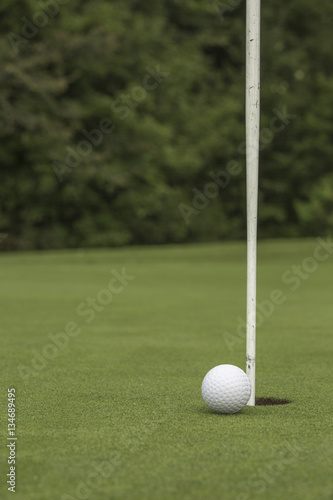 Golf ball close to pin and hole