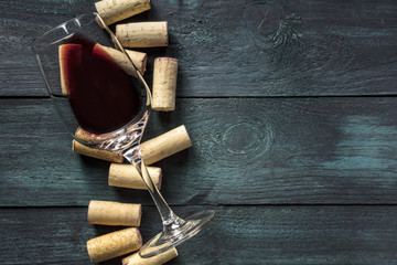 Glass of red wine and corks on dark background