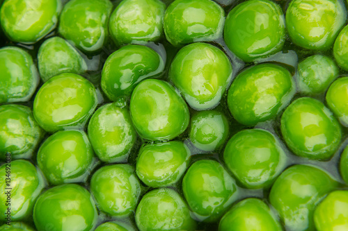 Wet fresh green peas in water closeup as background. Healthy vitamin food. © finepoints