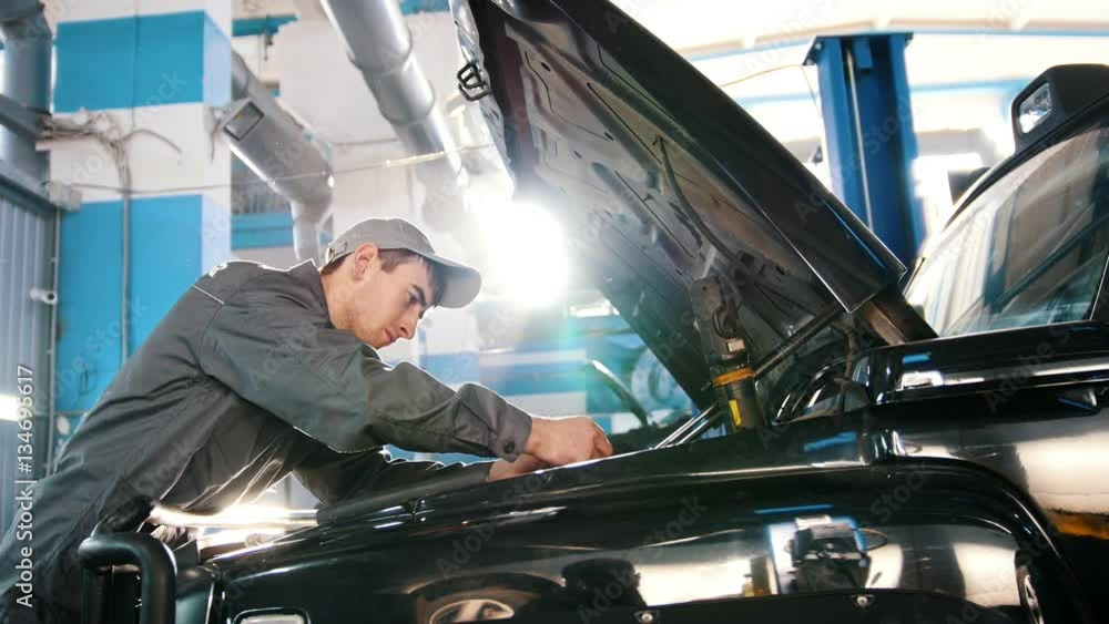 Mechanic in car service - repairing in engine compartment - slider shot Mechanic in car service - repairing in engine compartment - slider shot