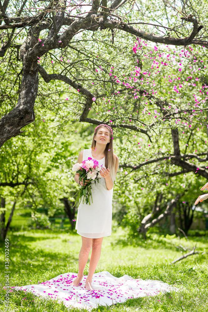 Gentle happy brunette woman with bouquet of peonies in among the trees a sunny day Gentle happy brunette woman with bouquet of peonies in among the trees a sunny day