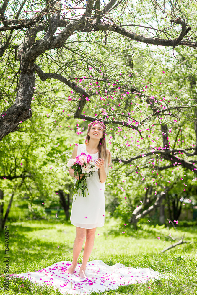Gentle happy brunette woman with bouquet of peonies in among the trees a sunny day Gentle happy brunette woman with bouquet of peonies in among the trees a sunny day