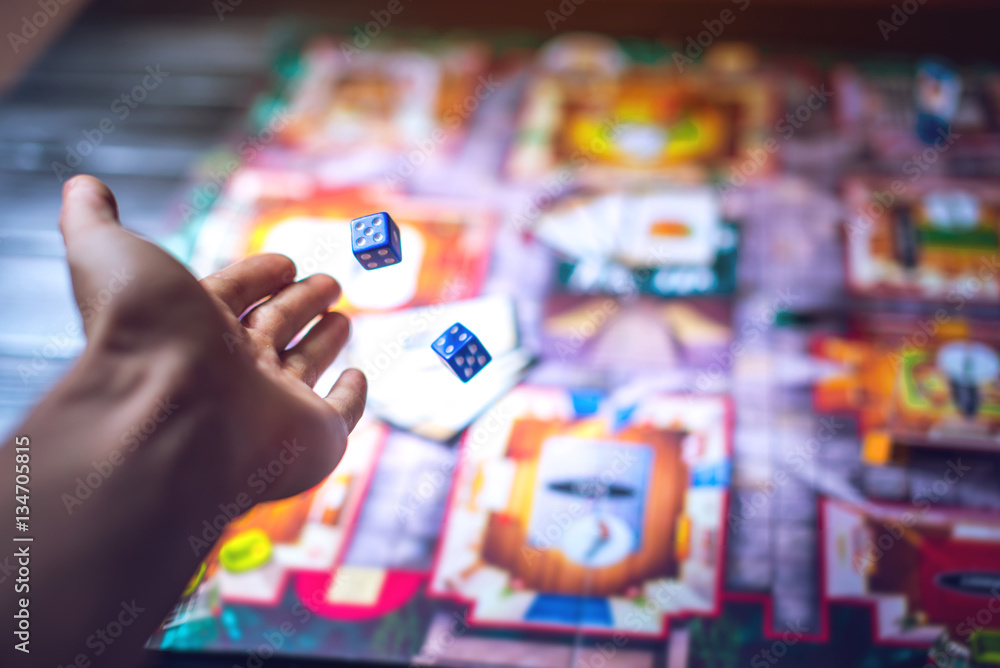 Hand throws the dice on the background of Board games - obrazy, fototapety, plakaty 