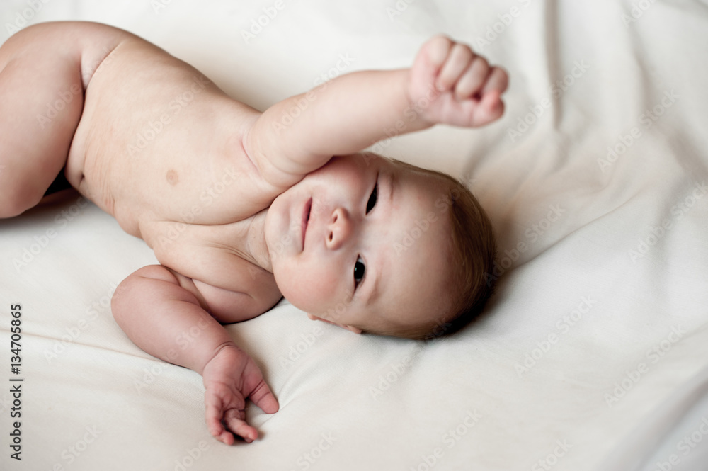 Soft picture of a beautiful baby boy laying on white bedding Soft picture of a beautiful baby boy laying on white bedding