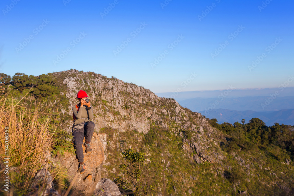 Woman hiker taking photo with mirrorless camera on mountain. Bac