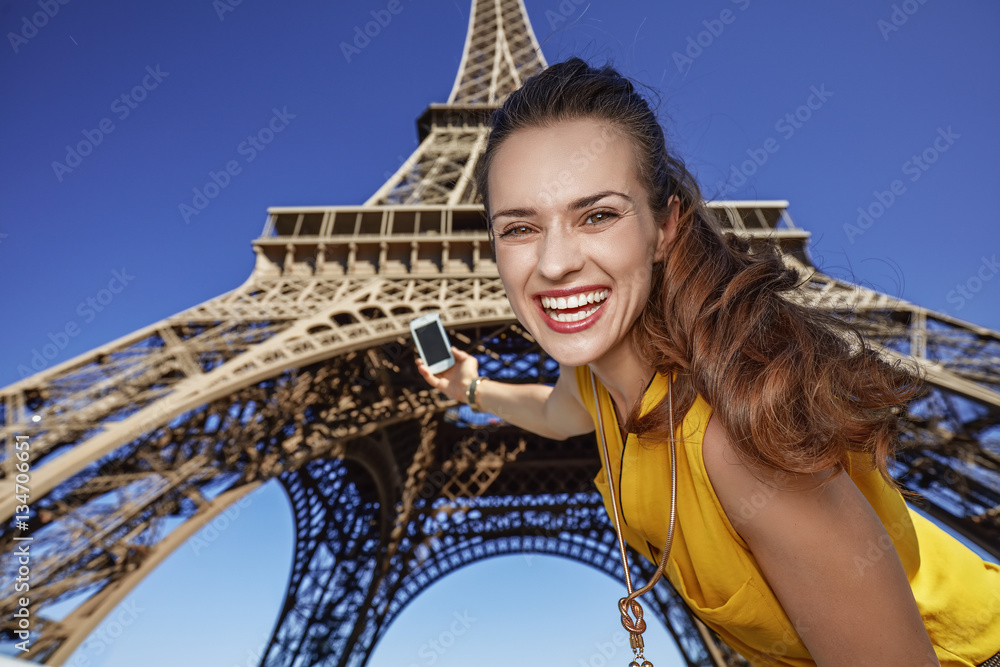 happy young woman taking selfie with phone in Paris, France