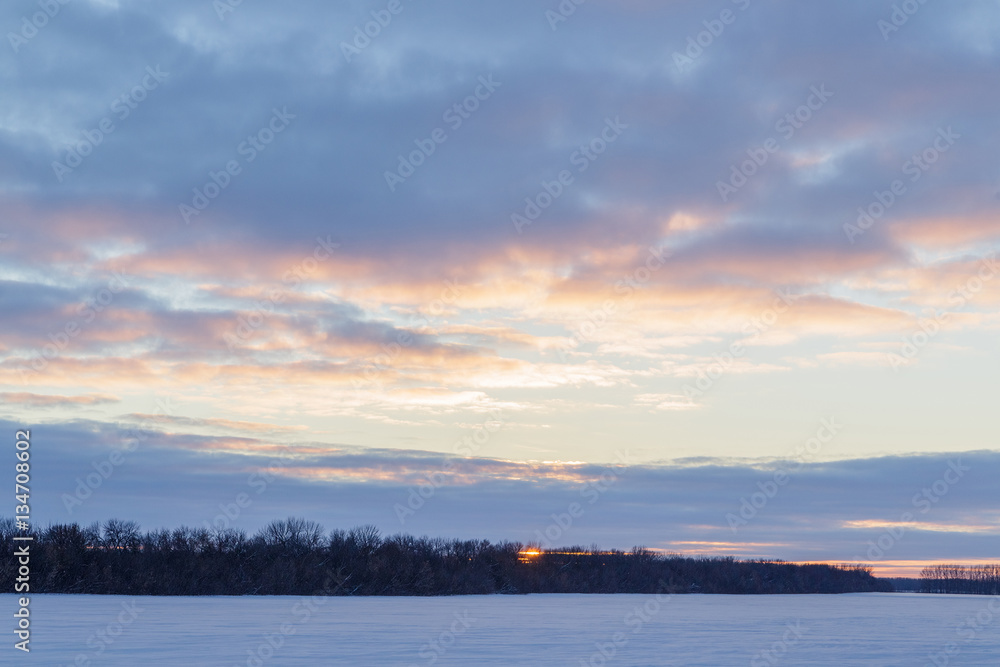 Winter sunset over snowy field.