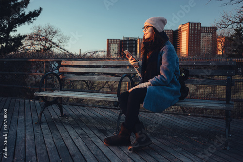 Young attractive girl in warm clothes holding mobile phone