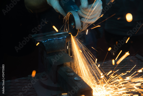 Worker cutting with grinder and welding metal with many sharp 