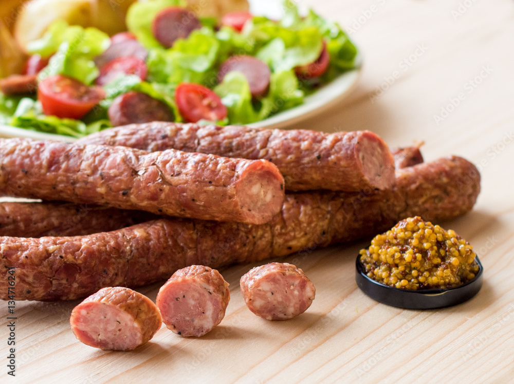 Smoked sausage with vegetables salad on a wooden board Smoked sausage with vegetables salad on a wooden board