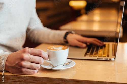 Cropped picture of young man in cafe drinking coffee