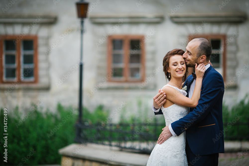 Naklejka premium Bride crosses her hands on groom's neck while they kiss on backy