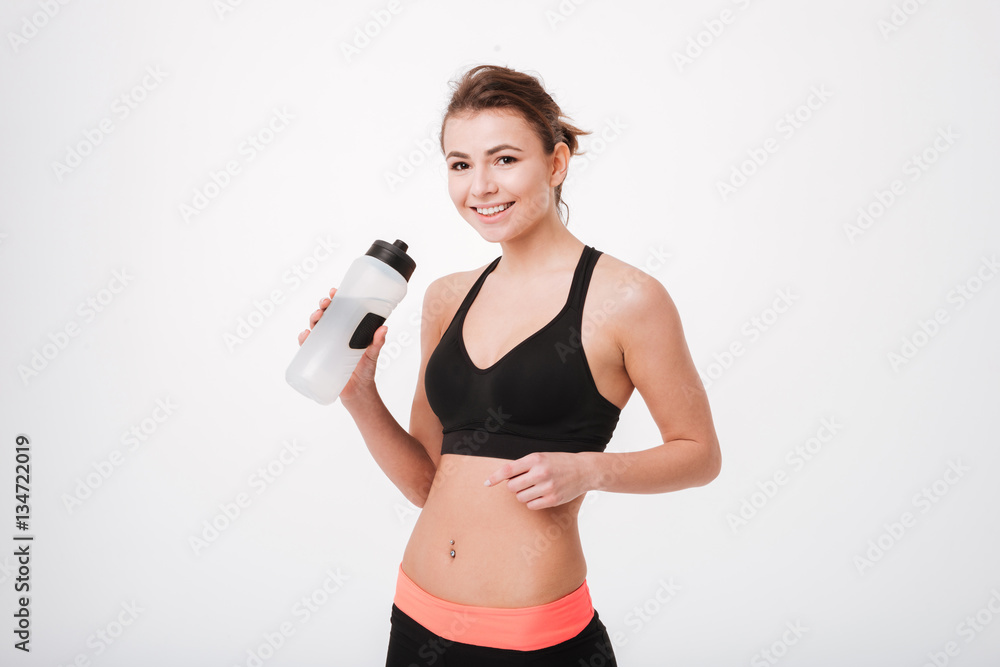 Smiling fitness woman holding water bottle and pointing finger away Smiling fitness woman holding water bottle and pointing finger away