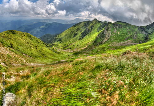 Bright alp mountain landscape with clouds and green grass.