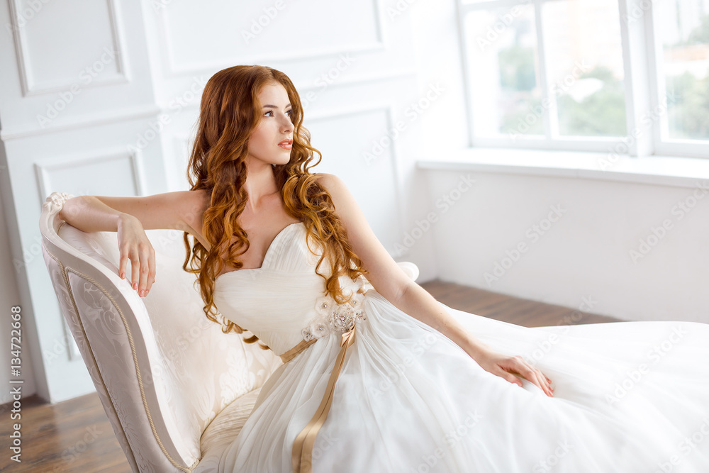 Bride in beautiful dress sitting resting on sofa indoors