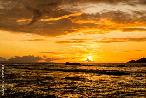 Extraordinay gold sunset with dramatic clouds in a tropical island, Anse Severe beach, La Digue, Seychelles photo