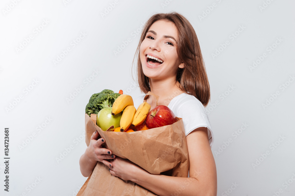 Cheerful young lady holding fruits and vegetables Cheerful young lady holding fruits and vegetables