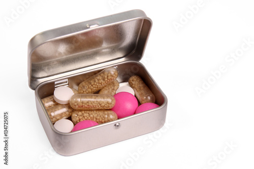 Brown, white and pink pills in a metal box isolated on white background 