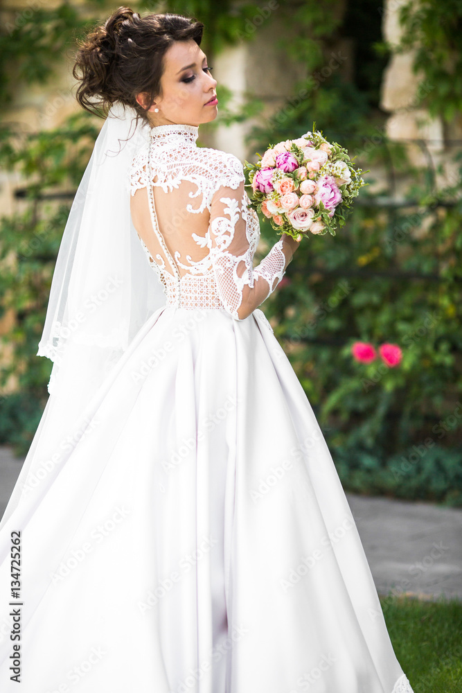 Bride in lace dress looks over her shoulder holding colorful wed