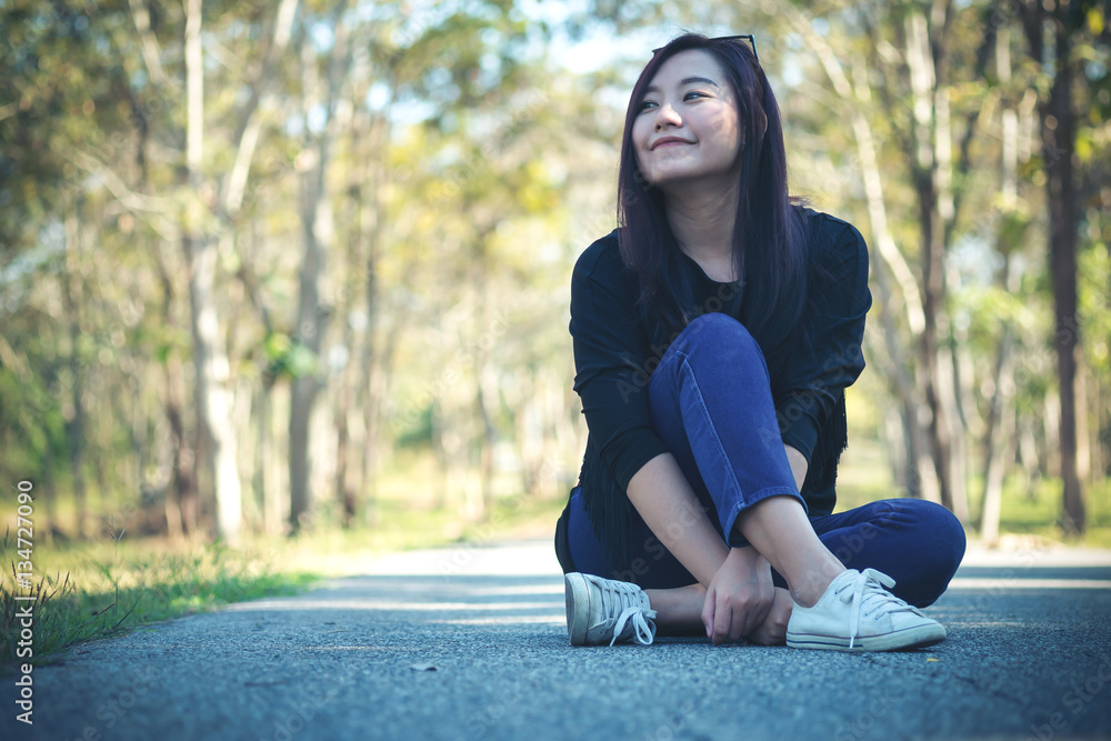 A beautiful asian woman sitting on the road with feeling happy and smiley face in green  nature background