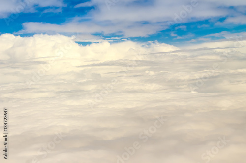 Beautiful cloudscape from sky aerial view. Beauty of nature view from above the sky and clouds. White clouds and blue sky view from airplane window. Sunlight in the sky shines on clouds.