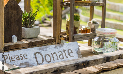 Wooden board with word donation and glass money jar