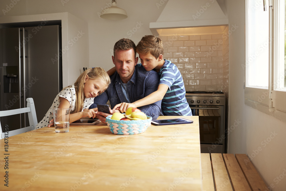 Fototapeta premium Children Looking At Mobile Phone With Father