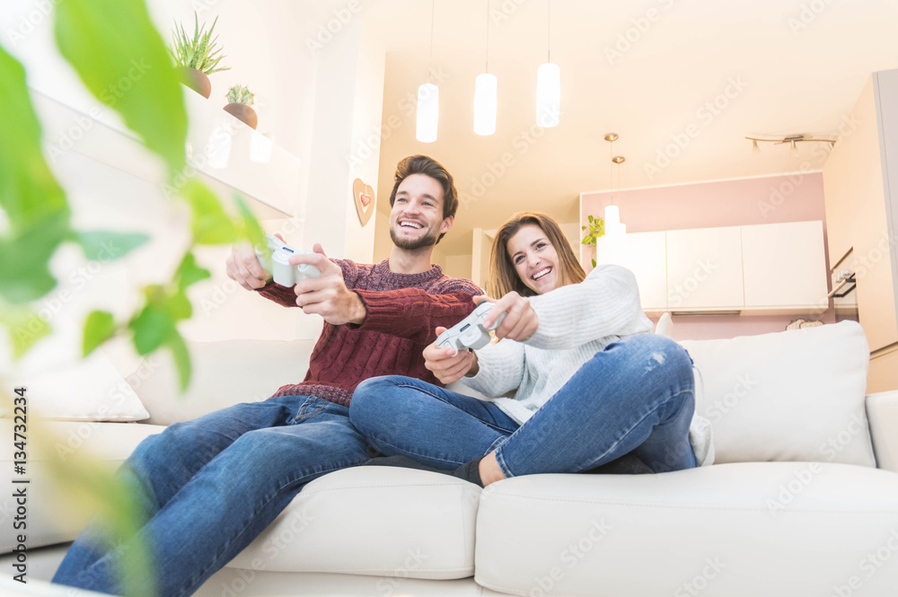 Couple having fun playing videogames at home.
