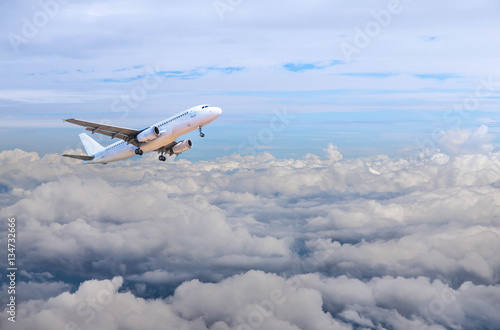 airplane flying away in to sky high altitude above the white clouds 