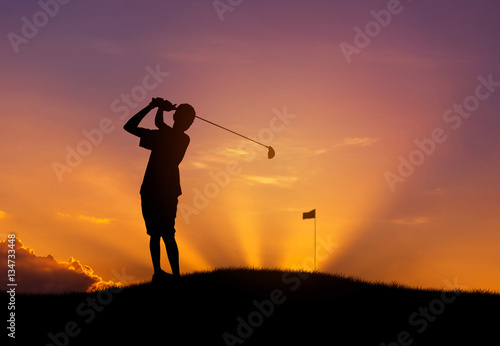silhouette the golfer hit golf ball toward the hole at sunset