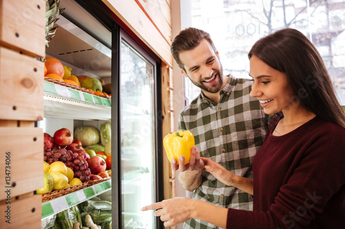Couple choosing and buying vegetables in grocery shop photo