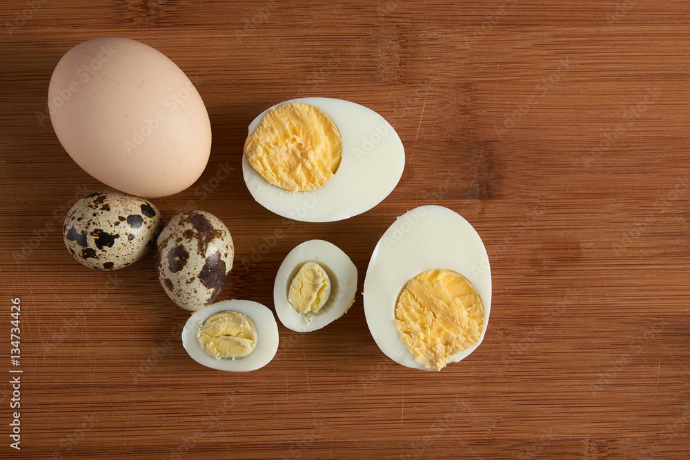 Halves of a boiled chicken and quail eggs on wooden background Halves of a boiled chicken and quail eggs on wooden background