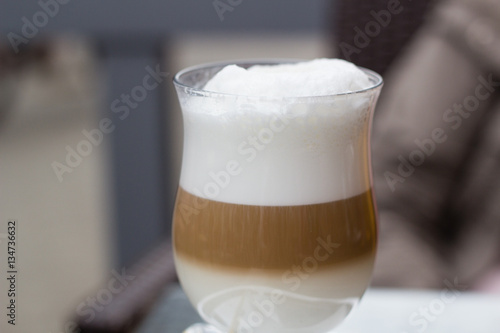 Layers of latte coffe in glass cup on table of cafe