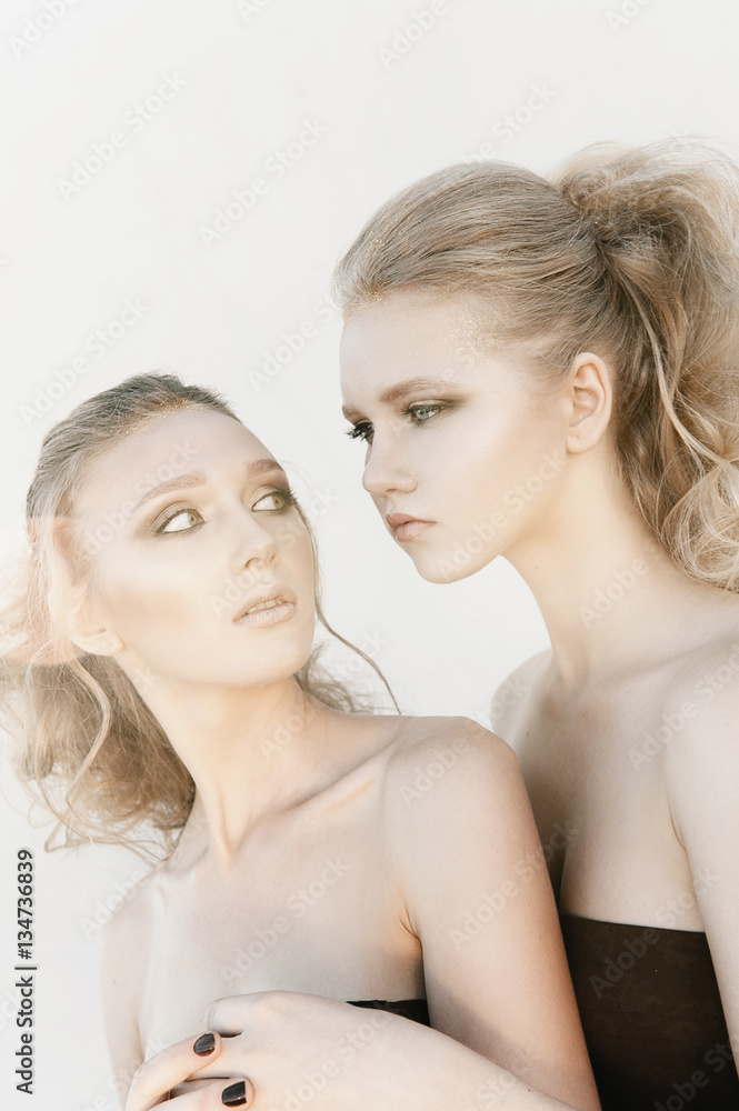 Glamour makeup two women with long hair style sitting on street wall background in dark. Fashion color portrait, retouched photo Glamour makeup two women with long hair style sitting on street wall background in dark. Fashion color portrait, retouched photo