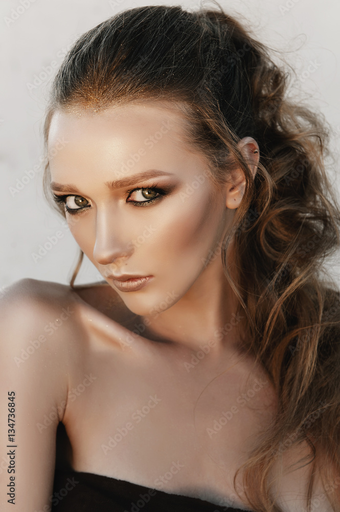 Glamour portrait of young fashion woman face with bright evening golden make up for party and tanned skin. Warm toning. Retouched close up portrait Glamour portrait of young fashion woman face with bright evening golden make up for party and tanned skin. Warm toning. Retouched close up portrait