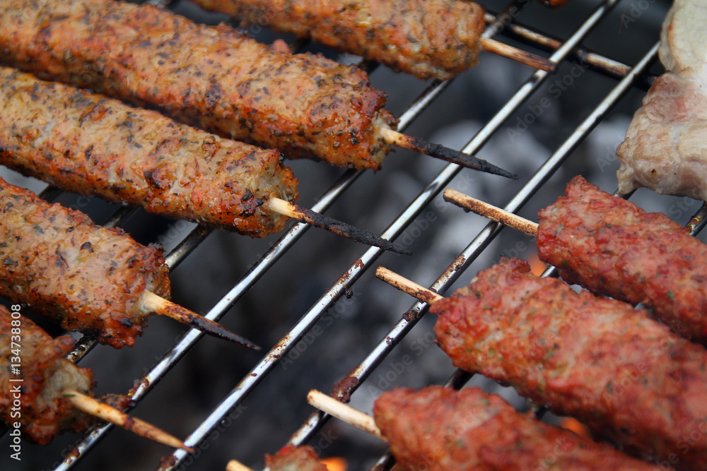Lamb kebab on skewer on barbecue in home garden.