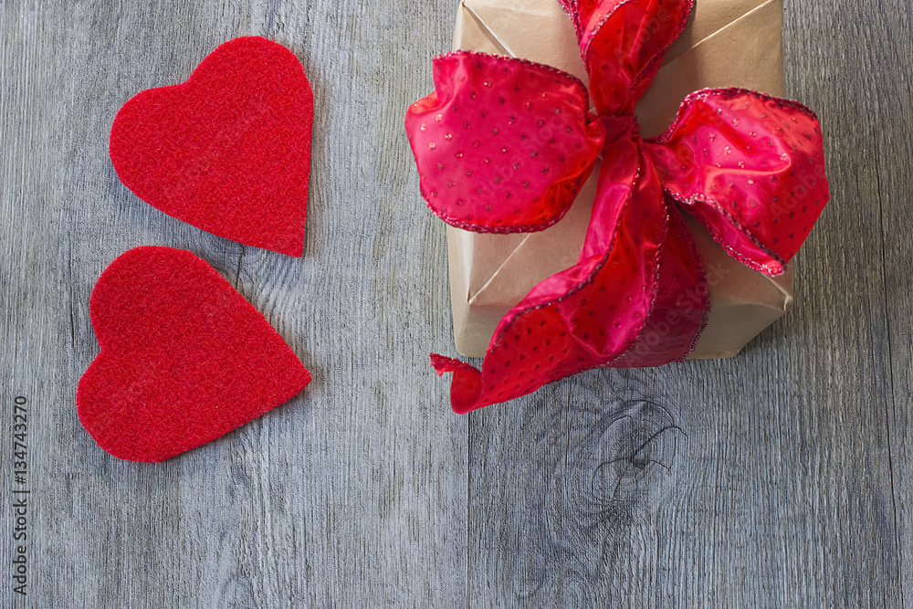 A two decorative red hearts and gift with red bow on gray wooden background A two decorative red hearts and gift with red bow on gray wooden background