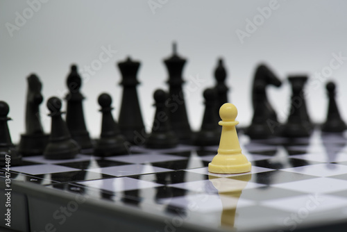 One chess pieces staying against full set of black chess pieces