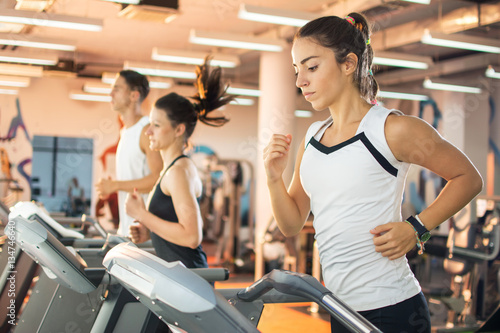 Canvas Print Young woman running on a treadmill at the gym.