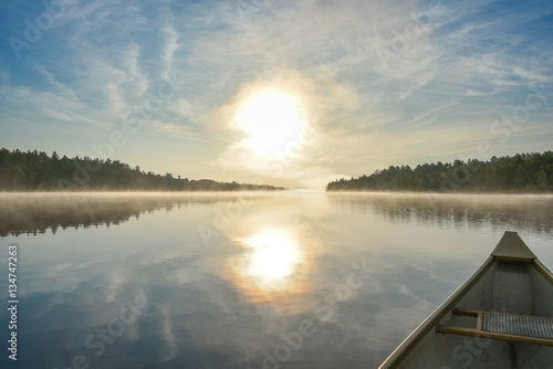 Canoe trip in the morning. Brilliant and bright mid-summer sunshine morning, paddling a canoe in the middle of quiet, calm and peaceful Corry lake.